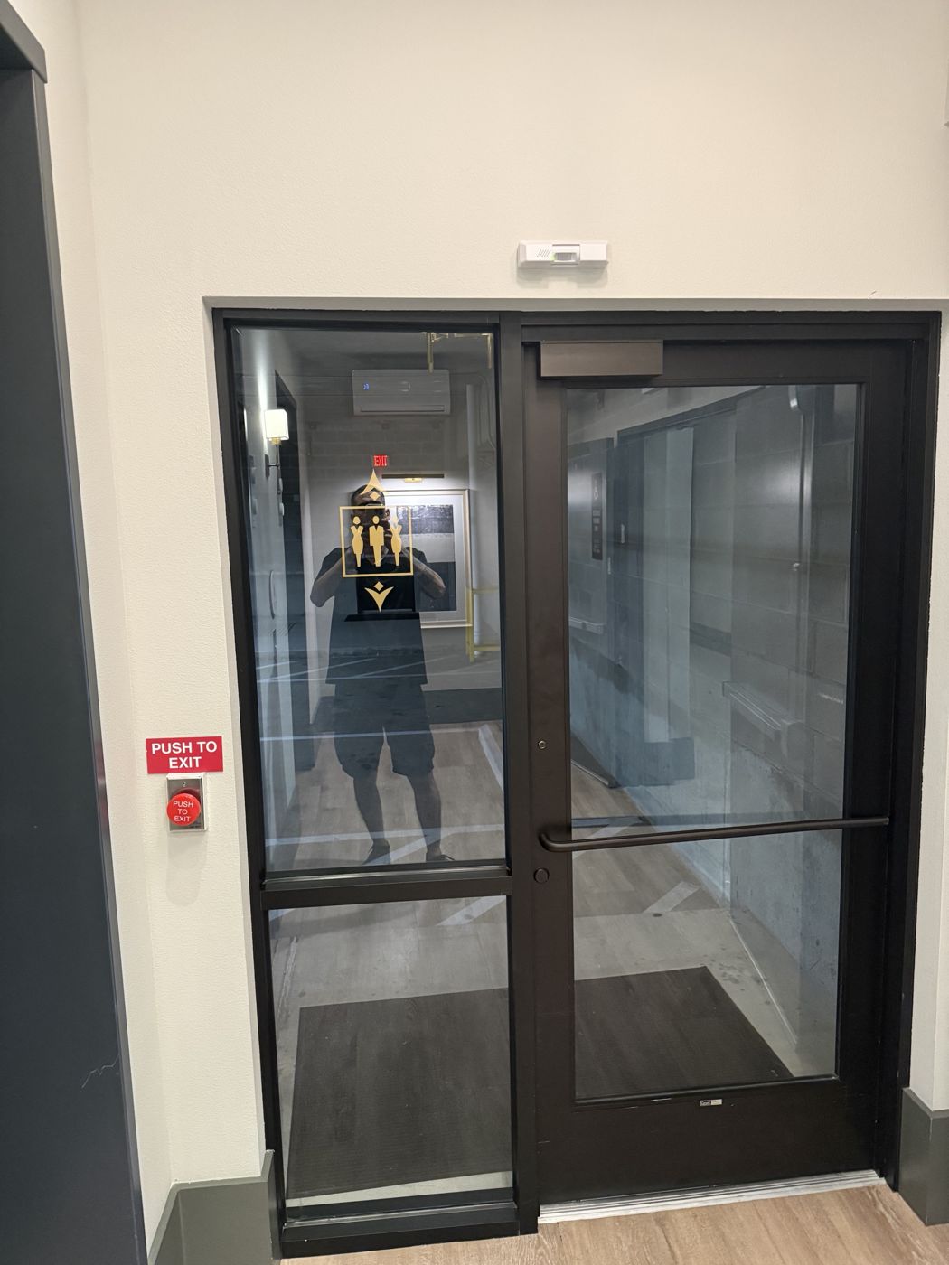 Access-controlled glass door with push-to-exit button and door closer installed by YNT Security Solutions